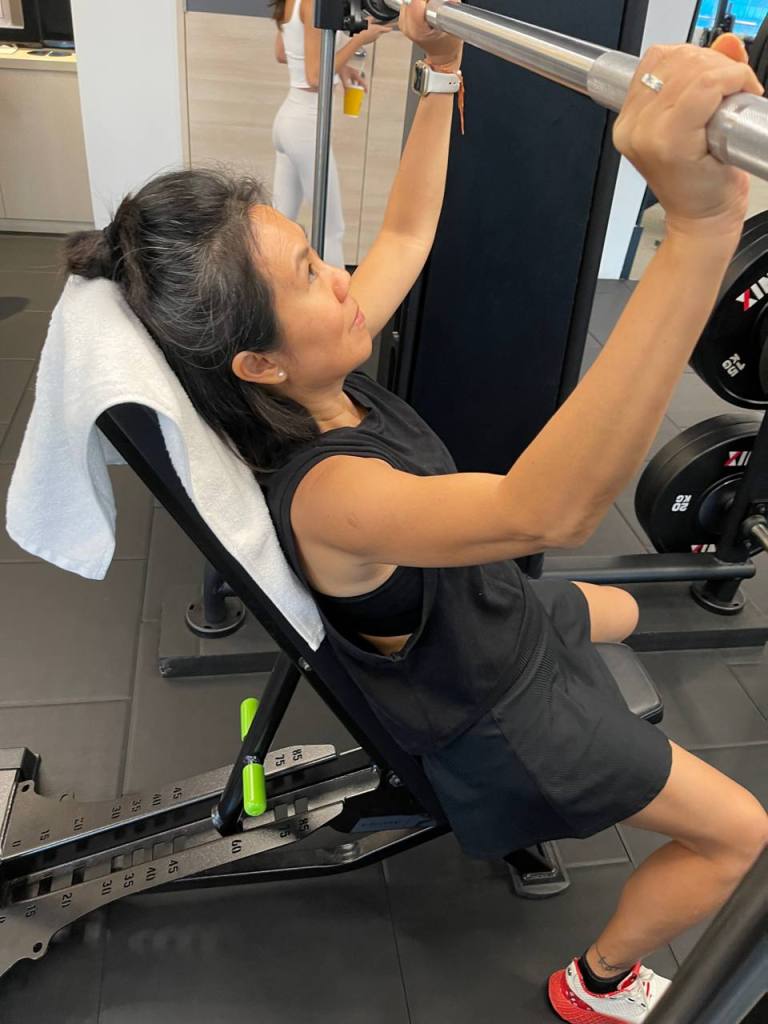 A person using a weight machine for strength training in a gym setting, focusing on their form while lifting.