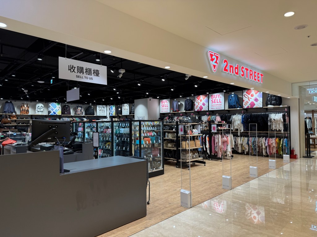 The interior of a secondhand store named '2nd STREET,' showcasing racks of clothing and accessories, with signage indicating buy and sell options.