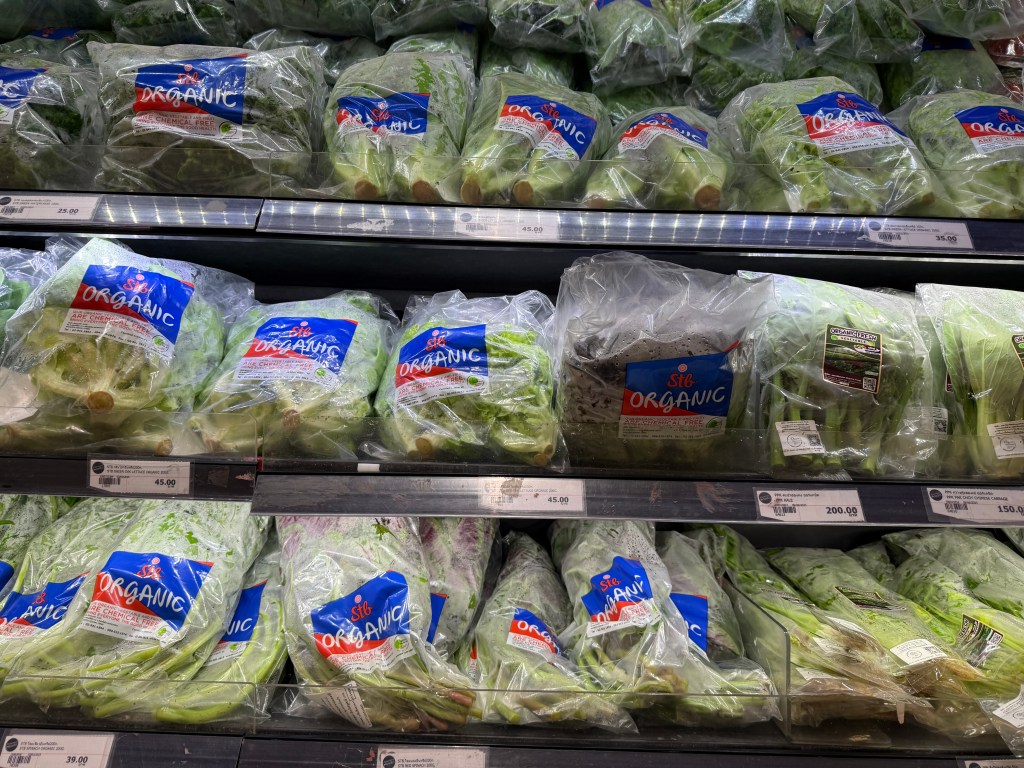 A variety of packaged organic vegetables displayed in a grocery store, showcasing labels indicating they are chemical-free.