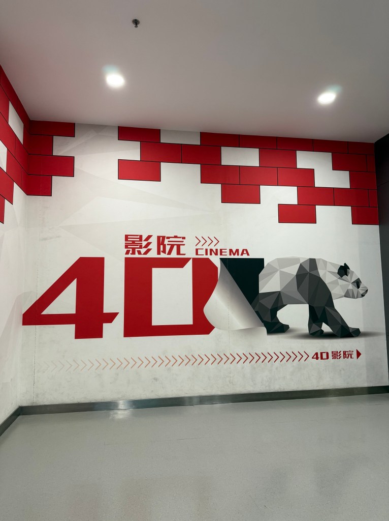An interior wall featuring a modern graphic design promoting a 4D cinema experience, with a stylized panda and bold red accents.