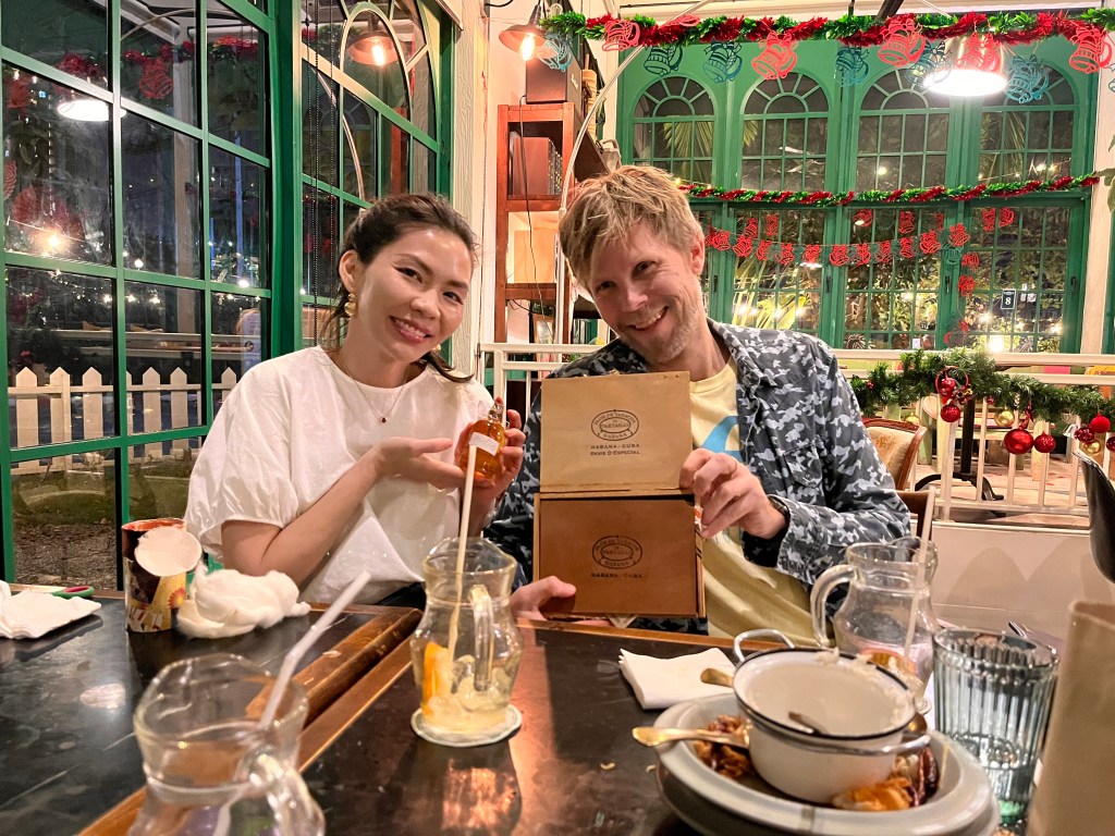 Two friends enjoying a meal together at a restaurant, smiling and holding a menu, with festive decorations in the background.
