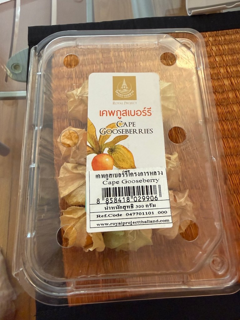 A plastic container of golden Cape Gooseberries with the Thai Royal Project label, showing the husk-covered premium fruit.