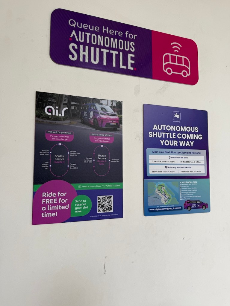 Promotional posters and signage for the Autonomous Shuttle trial in Punggol, including route maps and a QR code to sign up.