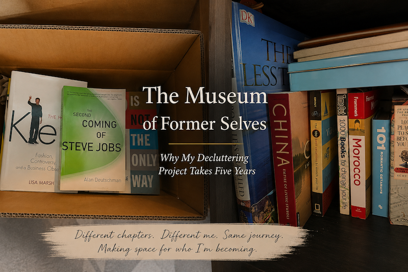 An open cardboard box containing business books next to a shelf of travel guides, illustrating a midlife decluttering project and intentional living.
