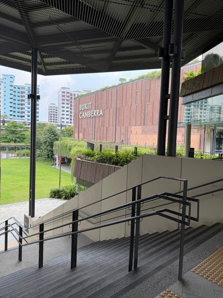An outdoor architectural view of the modern Bukit Canberra Sports Centre in Singapore, which houses the neighborhood's nutrition and wellness clinic.