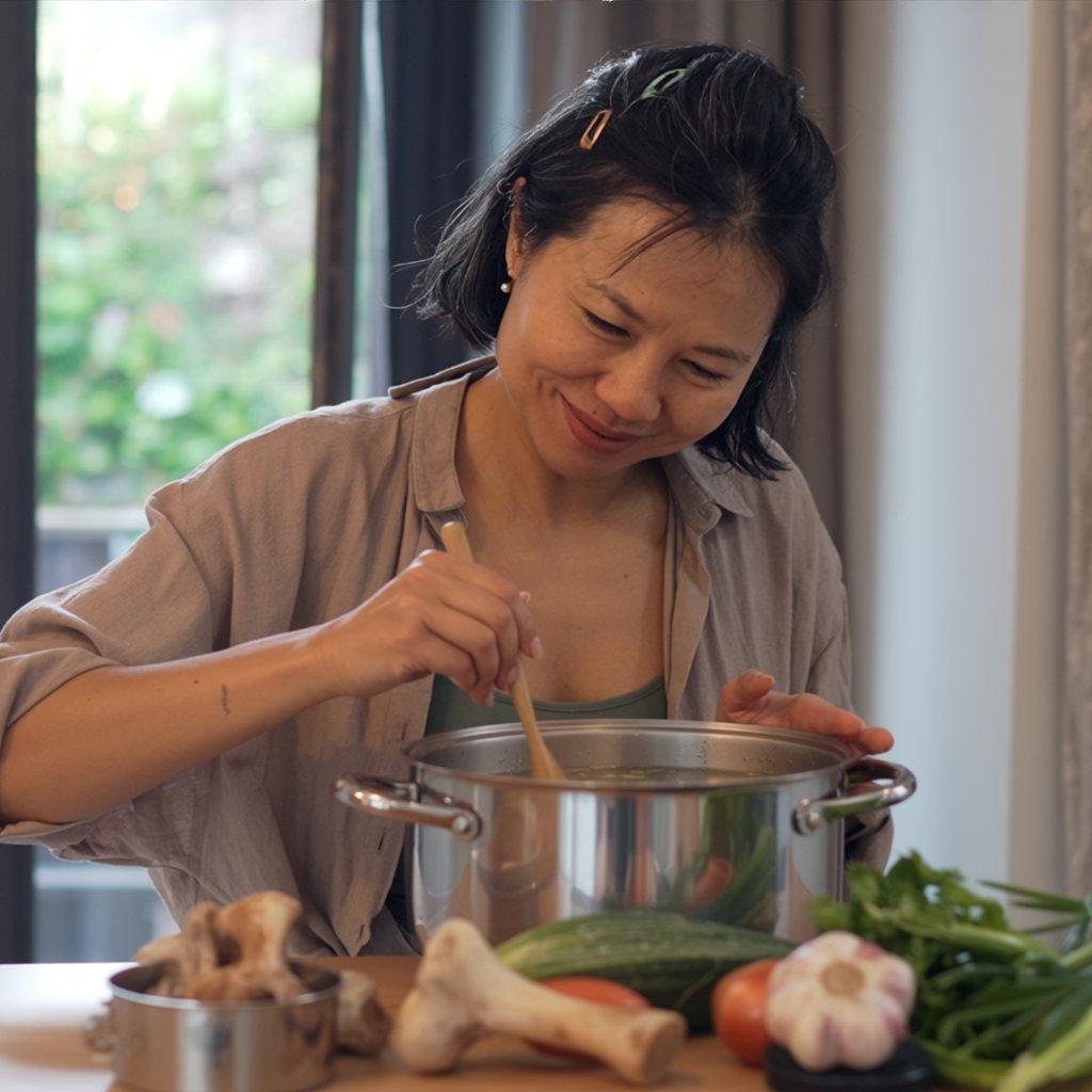 Preparing a nutrient-dense traditional TCM broth in a kitchen, showcasing intentional nutrition and proactive health habits.