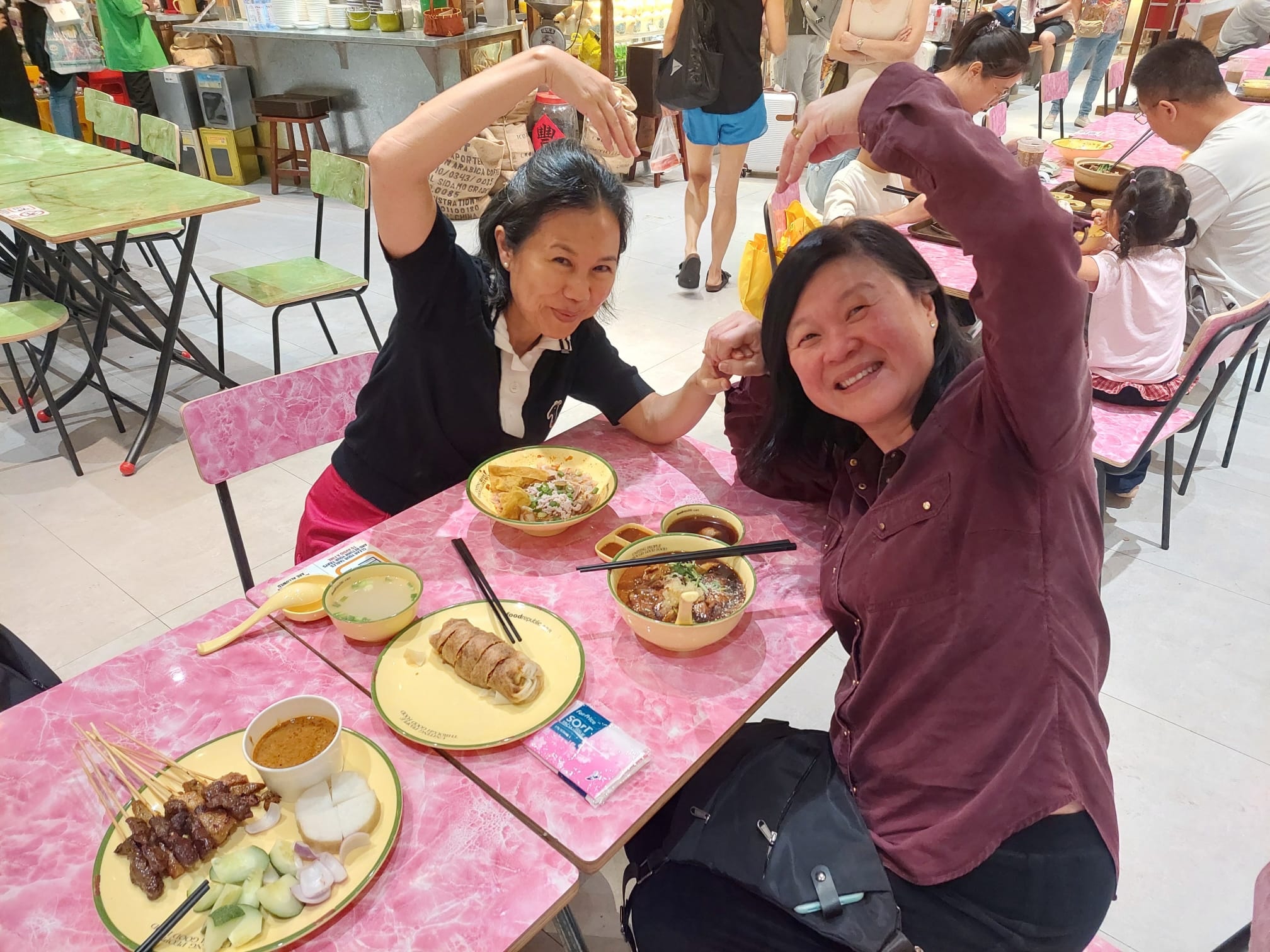Jane, the Ageisano blogger, sharing a meal and making a heart gesture with a close friend during a quick transit layover at Singapore Changi Airport.